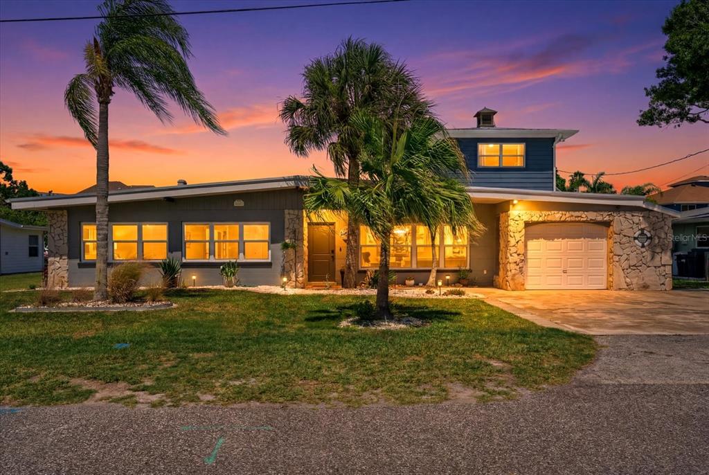 A single-story house with stone accents, a garage, and palm trees under a sunset sky — 512 PALM AVENUE, ELLENTON, FL