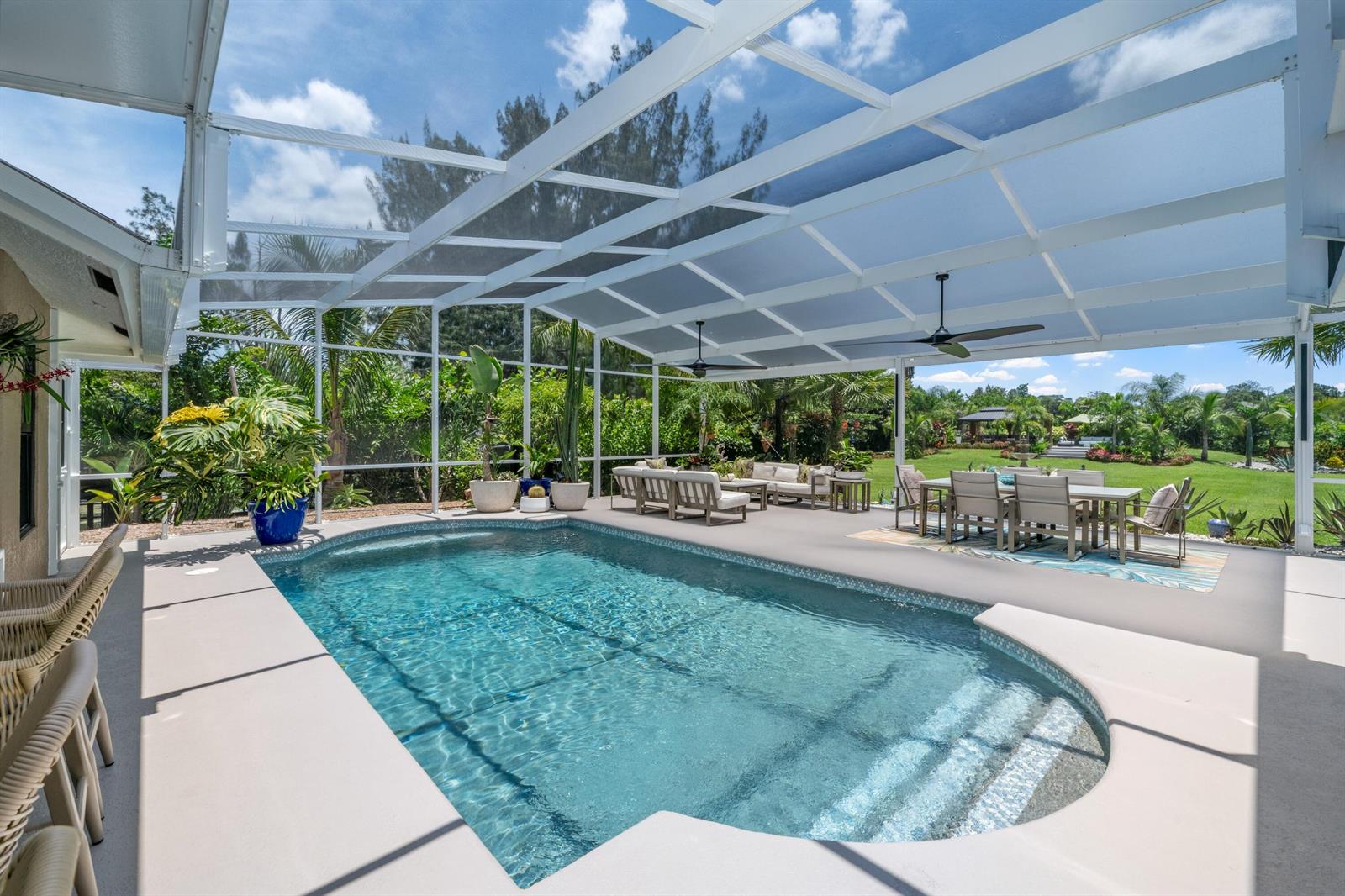 A screened-in patio features a swimming pool, outdoor dining area, and lounge seating — 14800 April Drive, FL 33470, FL