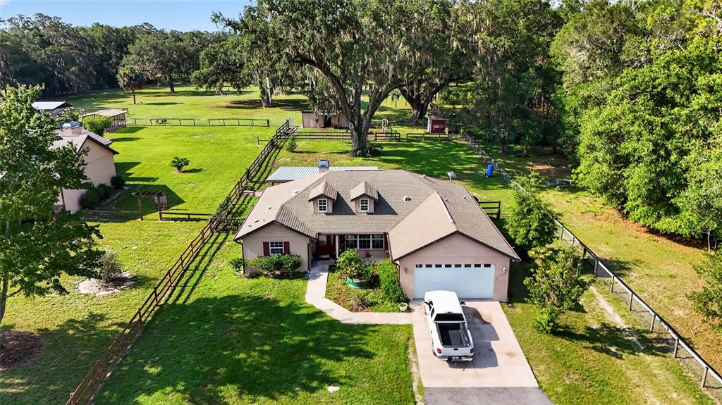 An aerial view shows a single-story house with a white garage and a fenced yard — 10844 SE HIGHWAY 42, SUMMERFIELD, FL
