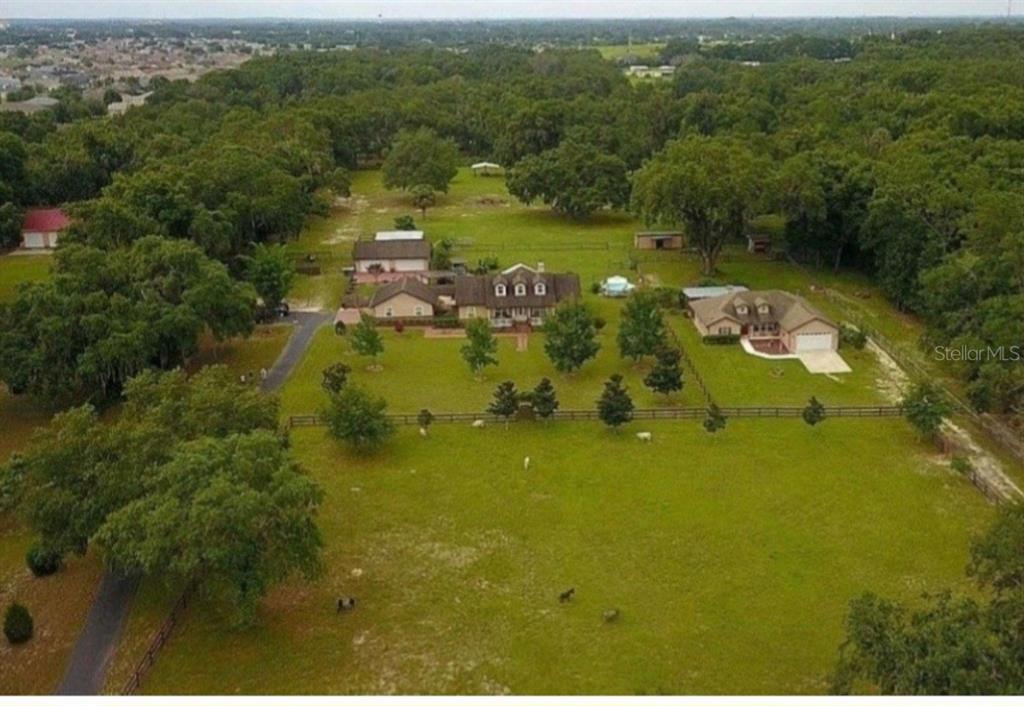 An aerial view shows a large house with a pool and outbuildings on a grassy lot — 10844 SE HIGHWAY 42, SUMMERFIELD, FL