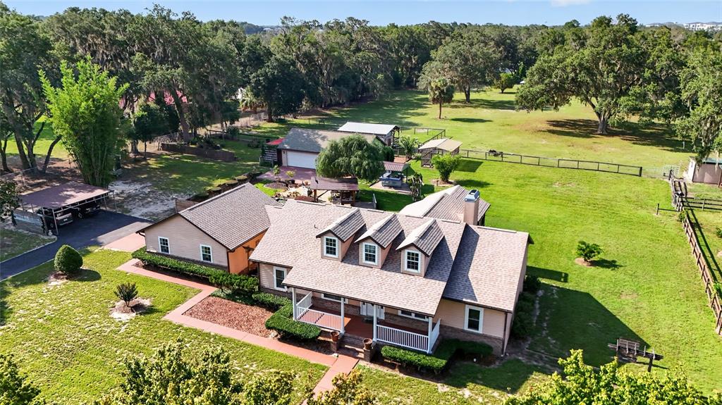 An aerial view shows a tan house with three dormers, a carport, and a detached garage — 10844 SE HIGHWAY 42, SUMMERFIELD, FL