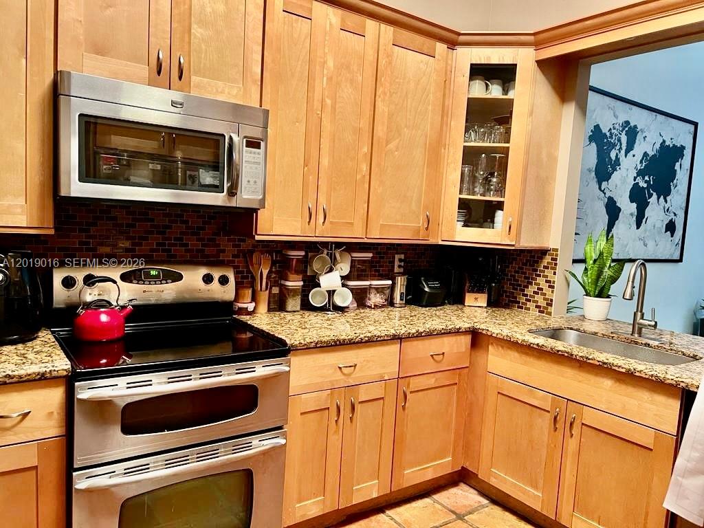 A kitchen features light wood cabinets, granite countertops, a stainless steel stove, and tiled backsplash — 509 NE 199th Ln # 3A, Miami FL 33179, MIAMI, FL