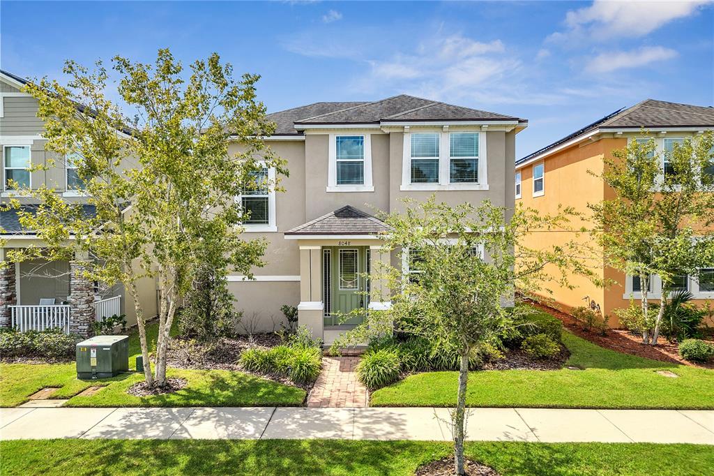 A two-story beige house with a green front door and a brick walkway — 8048 SCAGEL STREET, ORLANDO, FL