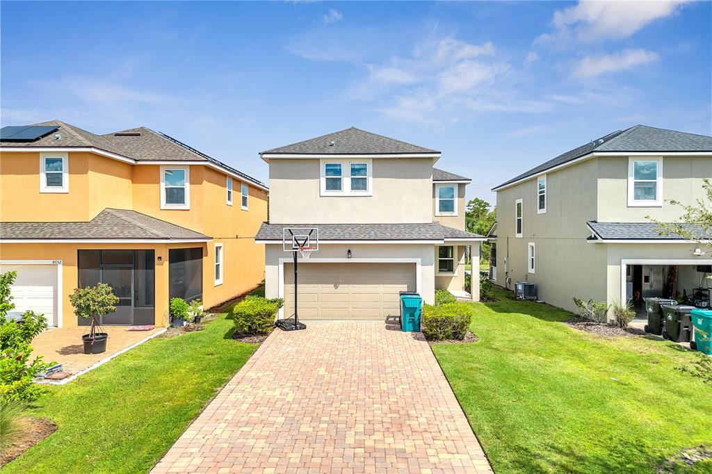 A two-story house with a beige exterior, a paved driveway, and a basketball hoop — 8048 SCAGEL STREET, ORLANDO, FL