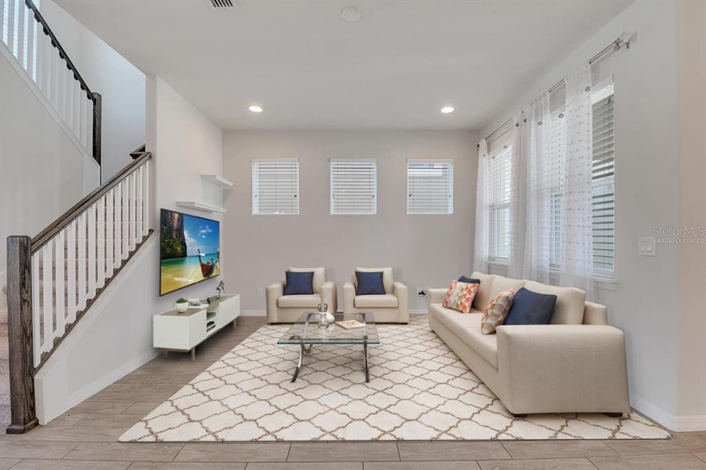 A living room features a sofa, two armchairs, a glass coffee table, and a television — 8048 SCAGEL STREET, ORLANDO, FL