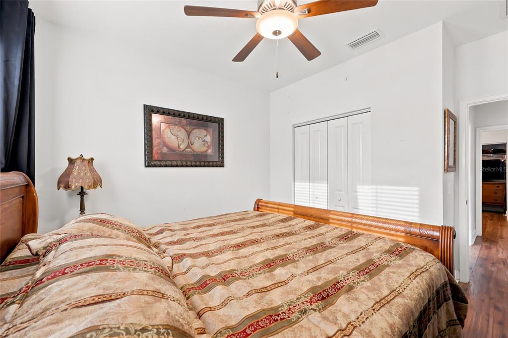 A bedroom features a wooden bed, a ceiling fan, and a framed world map print — 16634 NW 193RD TERRACE, HIGH SPRINGS, FL