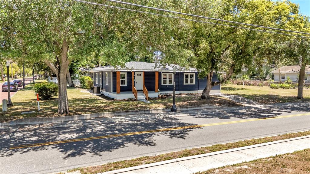 A blue single-story house with a front porch sits behind trees next to a road — 832 S CENTRAL AVENUE, LAKELAND, FL
