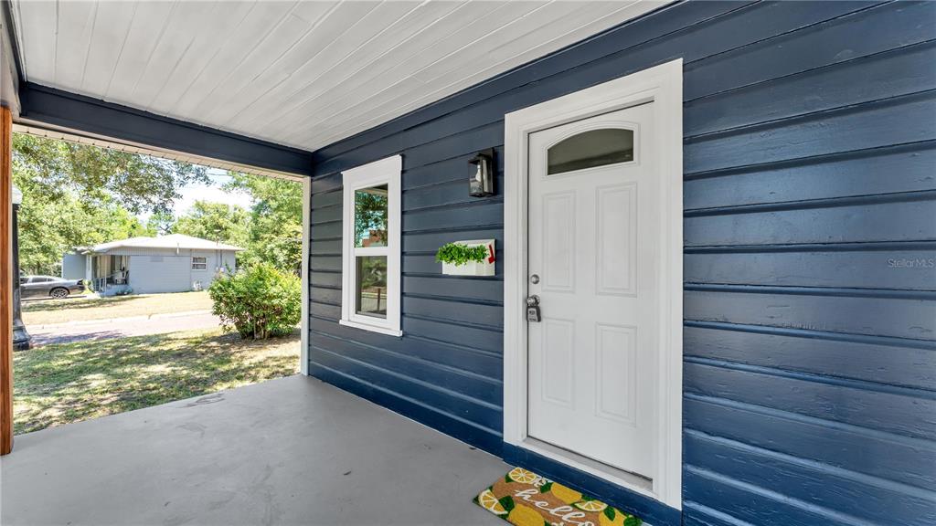 A covered porch with dark blue horizontal siding, a white front door, and a window — 832 S CENTRAL AVENUE, LAKELAND, FL