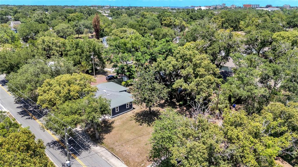 An aerial view shows a dark-colored house situated on a wooded lot near a road — 832 S CENTRAL AVENUE, LAKELAND, FL