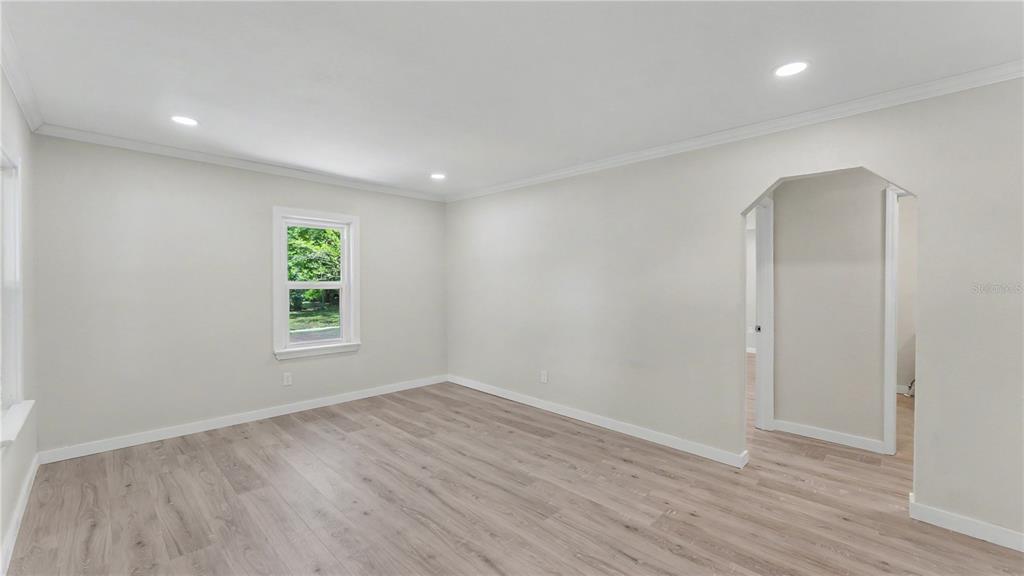 A room with light-colored walls, wood-look flooring, recessed lighting, and an arched doorway — 832 S CENTRAL AVENUE, LAKELAND, FL