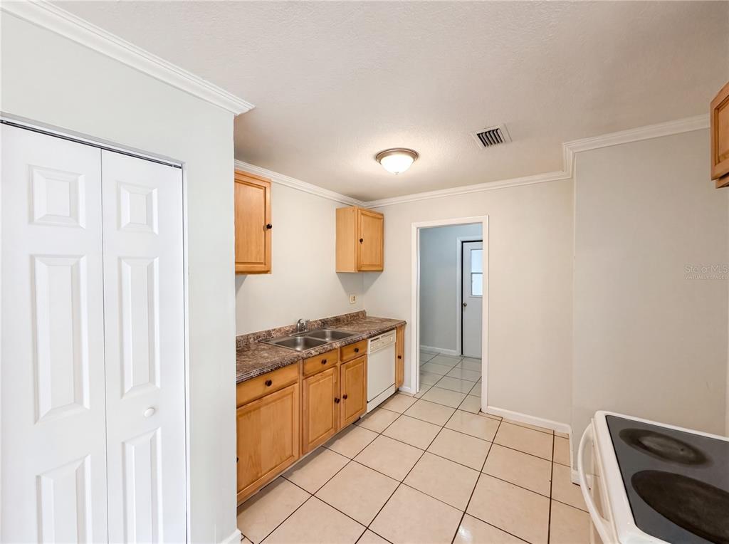 A kitchen with light wood cabinets, laminate countertops, white appliances, and beige tile flooring — 15246 SW 43RD TERRACE ROAD, OCALA, FL