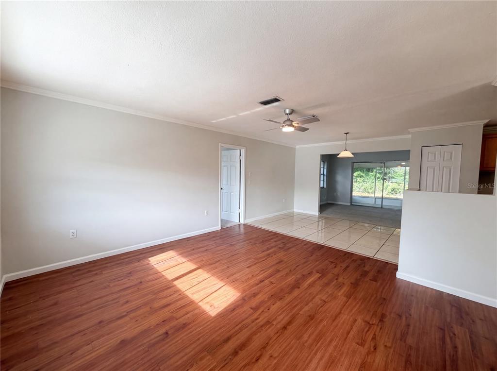 An open-concept living area features wood-look flooring, a ceiling fan, and a tiled dining space — 15246 SW 43RD TERRACE ROAD, OCALA, FL