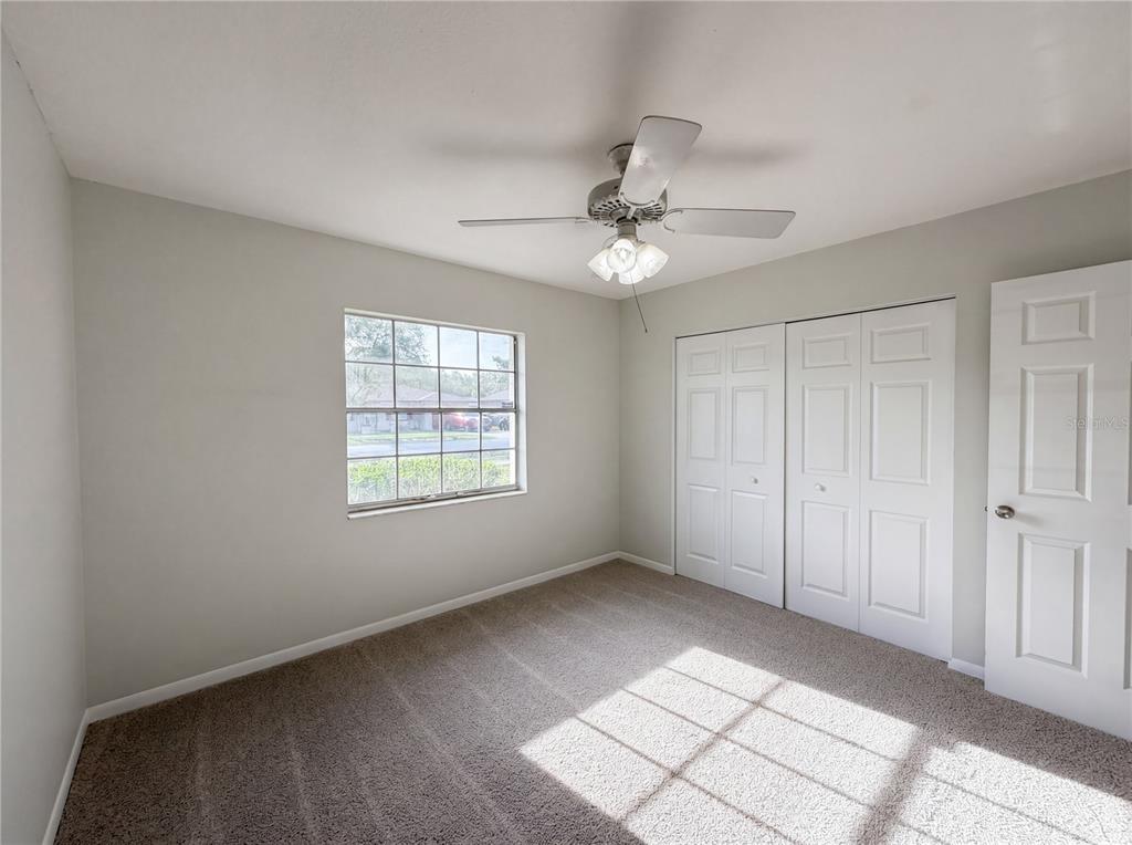 A bedroom with light gray walls, carpeted flooring, a ceiling fan, and a white closet — 15246 SW 43RD TERRACE ROAD, OCALA, FL