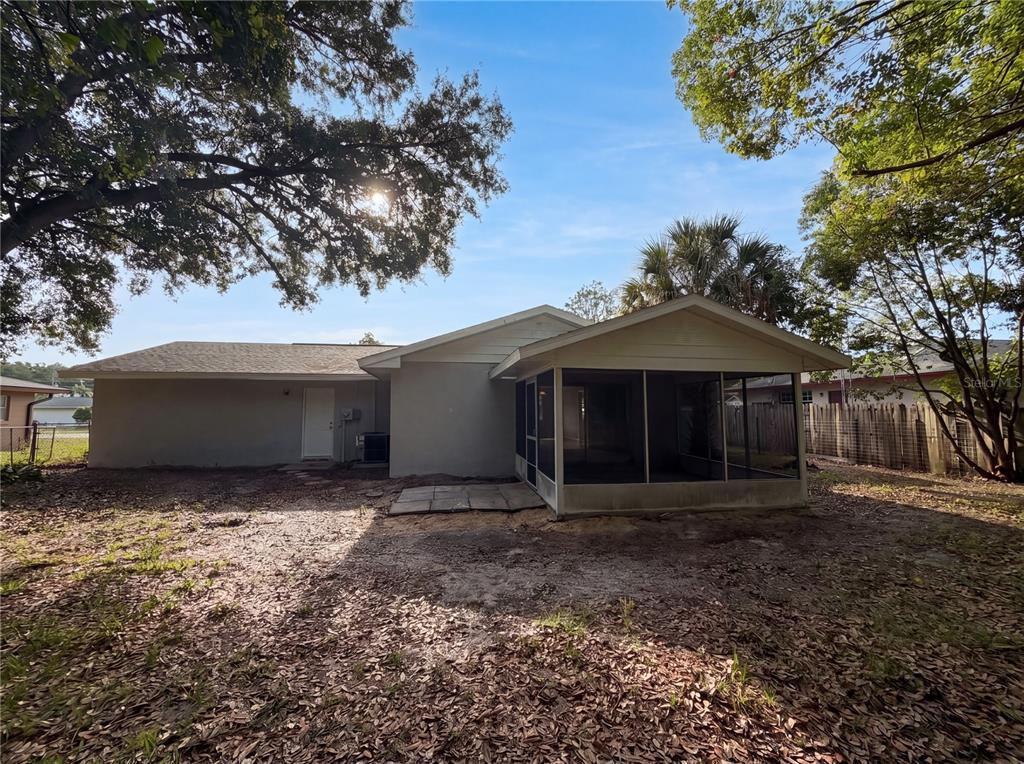 The backyard of a house features a screened-in porch and a concrete patio area — 15246 SW 43RD TERRACE ROAD, OCALA, FL