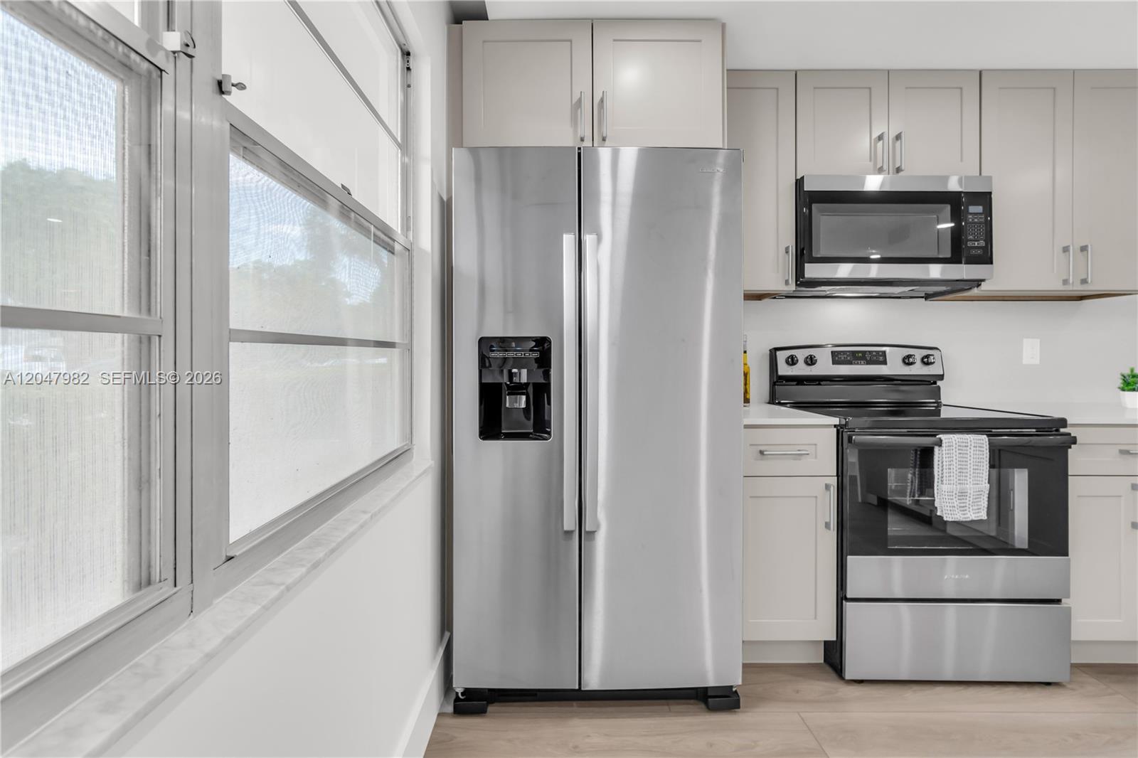 A kitchen features stainless steel appliances, light gray cabinets, and a window on the left — 2101 Lucaya Bnd # E1, Coconut Creek FL 33066, COCONUT CREEK, FL
