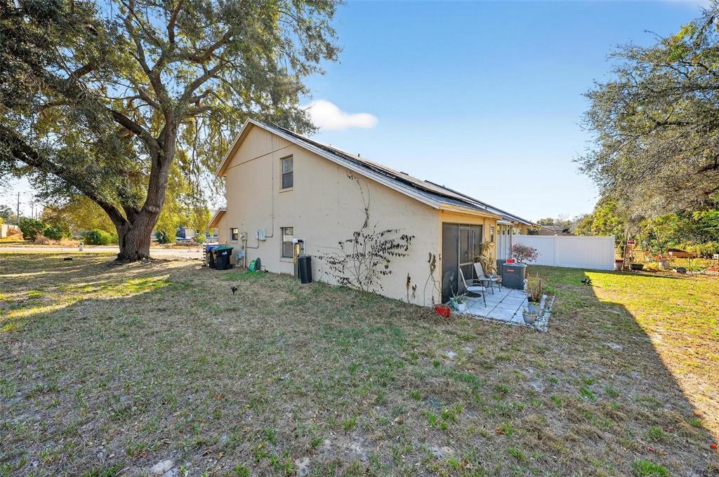 The exterior of a two-story house features a small patio, a screened enclosure, and landscaping — 1300 WOODMAN WAY, ORLANDO, FL