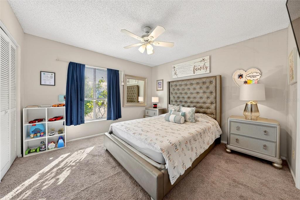A bedroom features a tufted headboard, a white storage unit, and a window with blue curtains — 1300 WOODMAN WAY, ORLANDO, FL