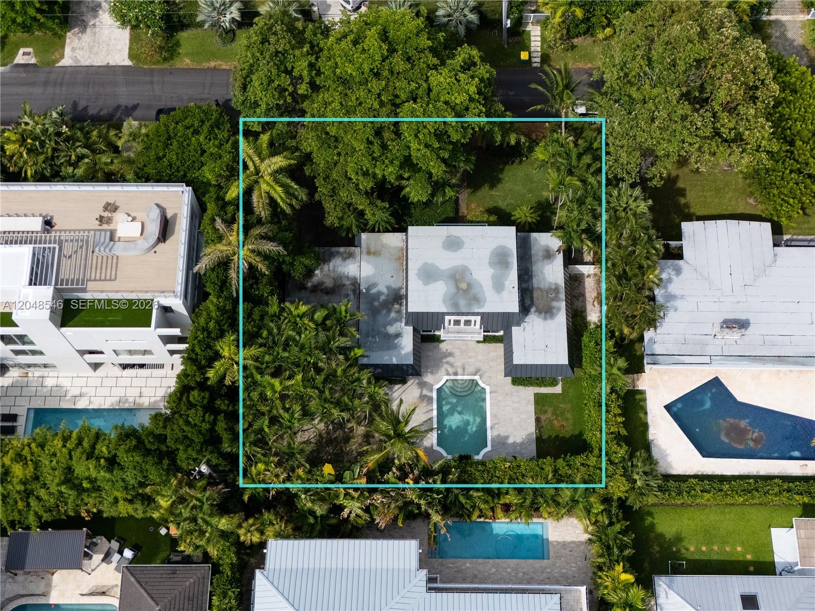 An aerial view shows a house with a swimming pool surrounded by lush trees — KEY BISCAYNE, FL