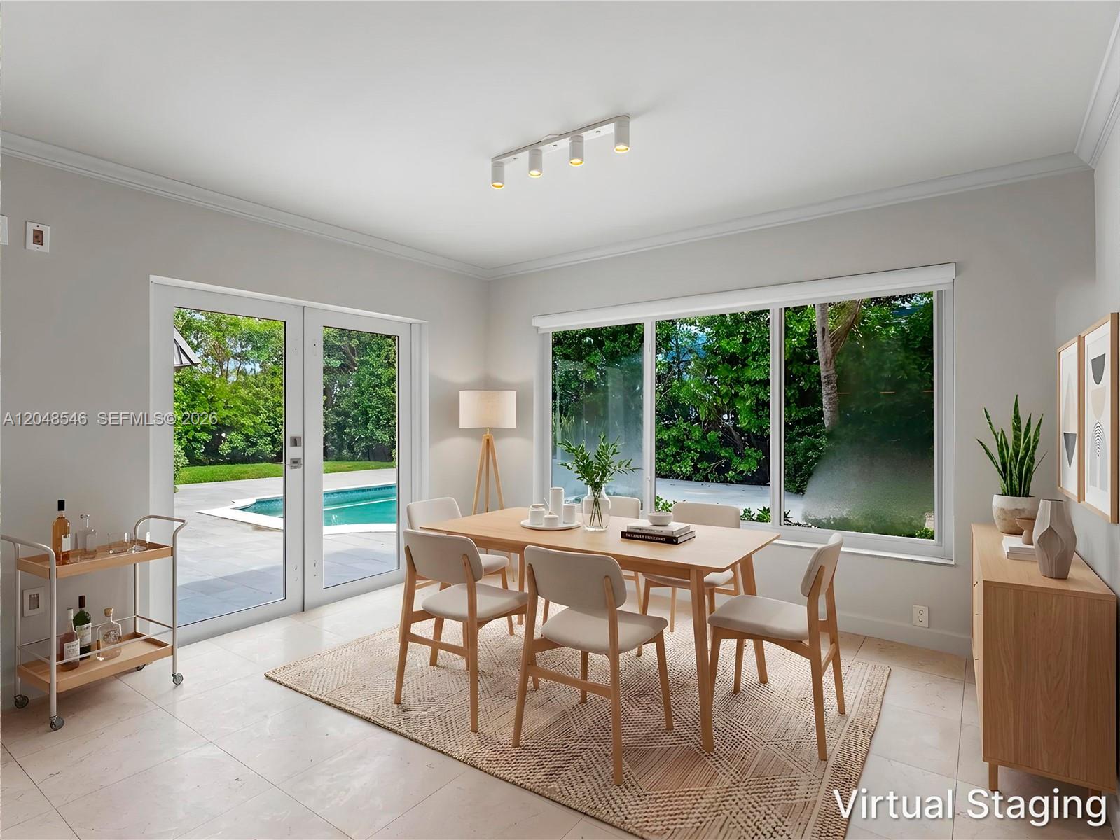 A dining room with a wooden table, chairs, and large windows overlooking a swimming pool — KEY BISCAYNE, FL