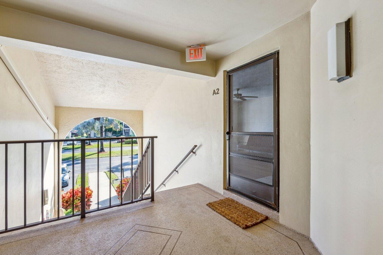 An outdoor apartment landing features a brown door labeled A2, a railing, and stairs — 618 Sea Pine Way # A2, FL 33415, FL