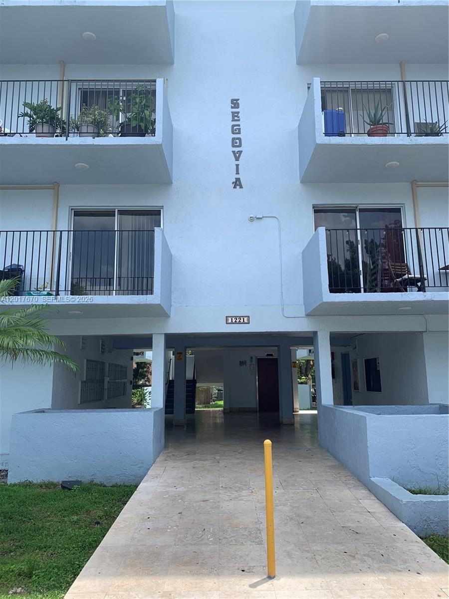 The exterior of a light blue multi-story apartment building features balconies and a central entrance — 1221 SW 122nd Ave # 207, Miami FL 33184, MIAMI, FL