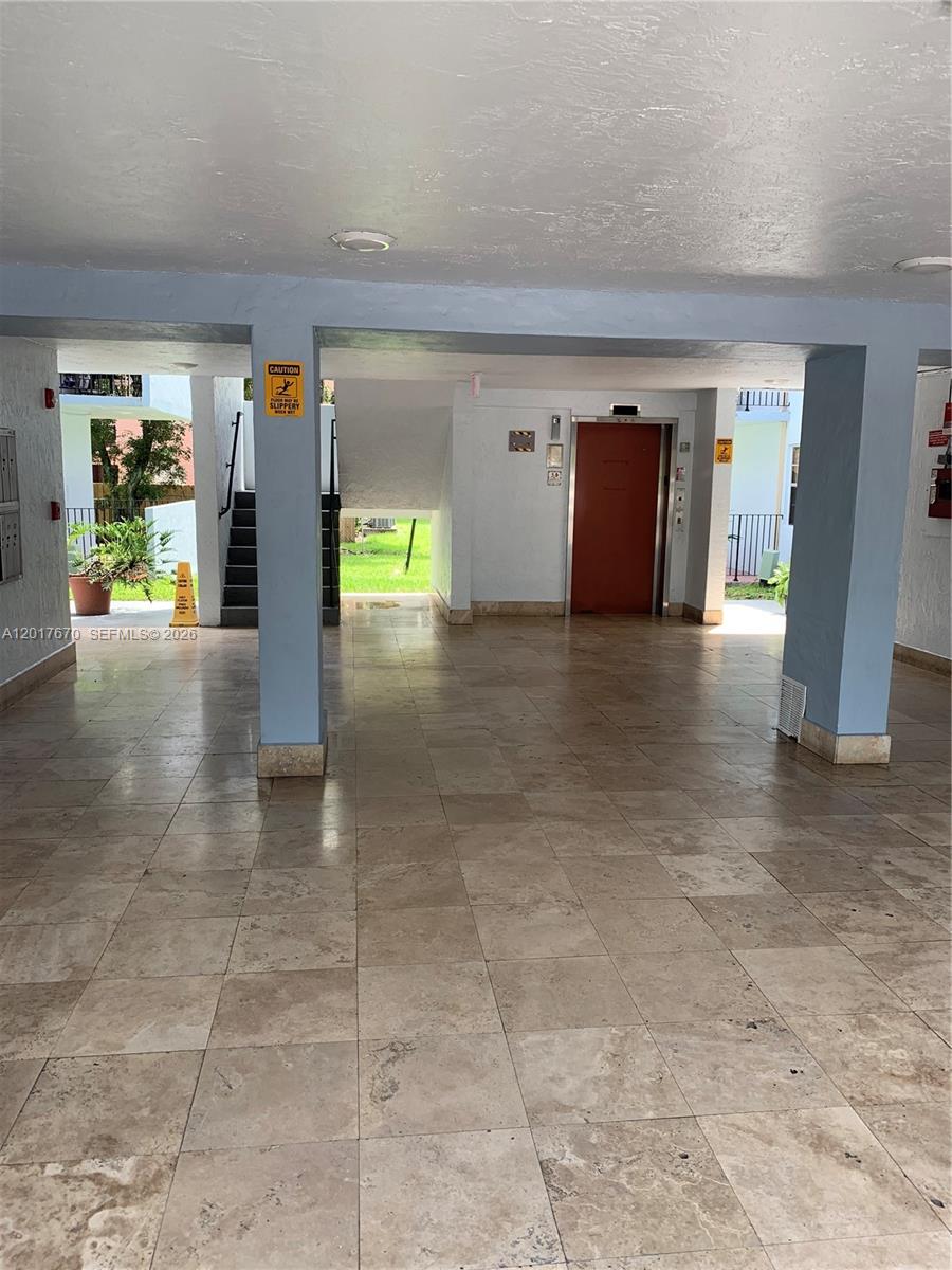 This covered building entrance features tiled flooring, a central elevator, and an adjacent staircase — 1221 SW 122nd Ave # 207, Miami FL 33184, MIAMI, FL