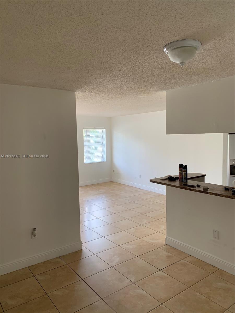 A tiled living area features a breakfast bar and a window with white blinds — 1221 SW 122nd Ave # 207, Miami FL 33184, MIAMI, FL