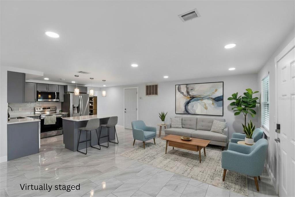 A virtually staged open-concept living room and kitchen with gray cabinets and light tile flooring — 4234 FLORAMAR TERRACE, NEW PORT RICHEY, FL