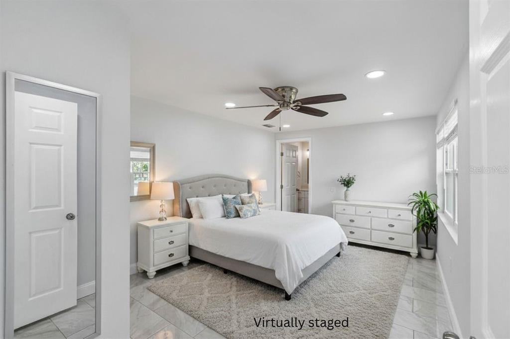 A virtually staged bedroom features a bed, white furniture, a ceiling fan, and tiled floors — 4234 FLORAMAR TERRACE, NEW PORT RICHEY, FL