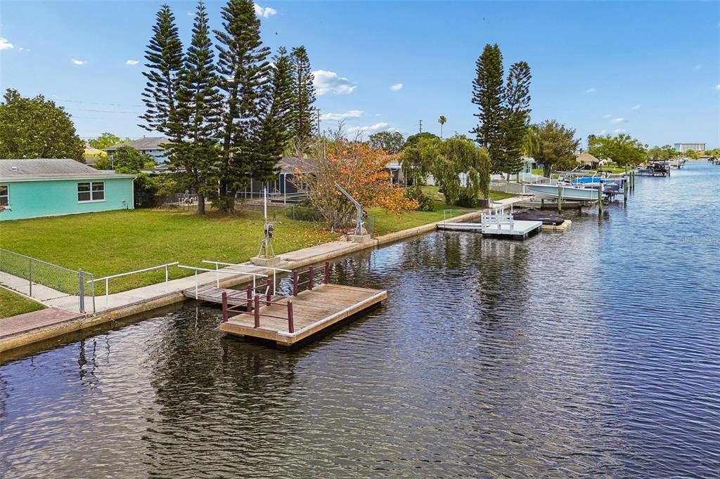 A waterfront property features a wooden dock, a concrete seawall, and a turquoise house — 4234 FLORAMAR TERRACE, NEW PORT RICHEY, FL