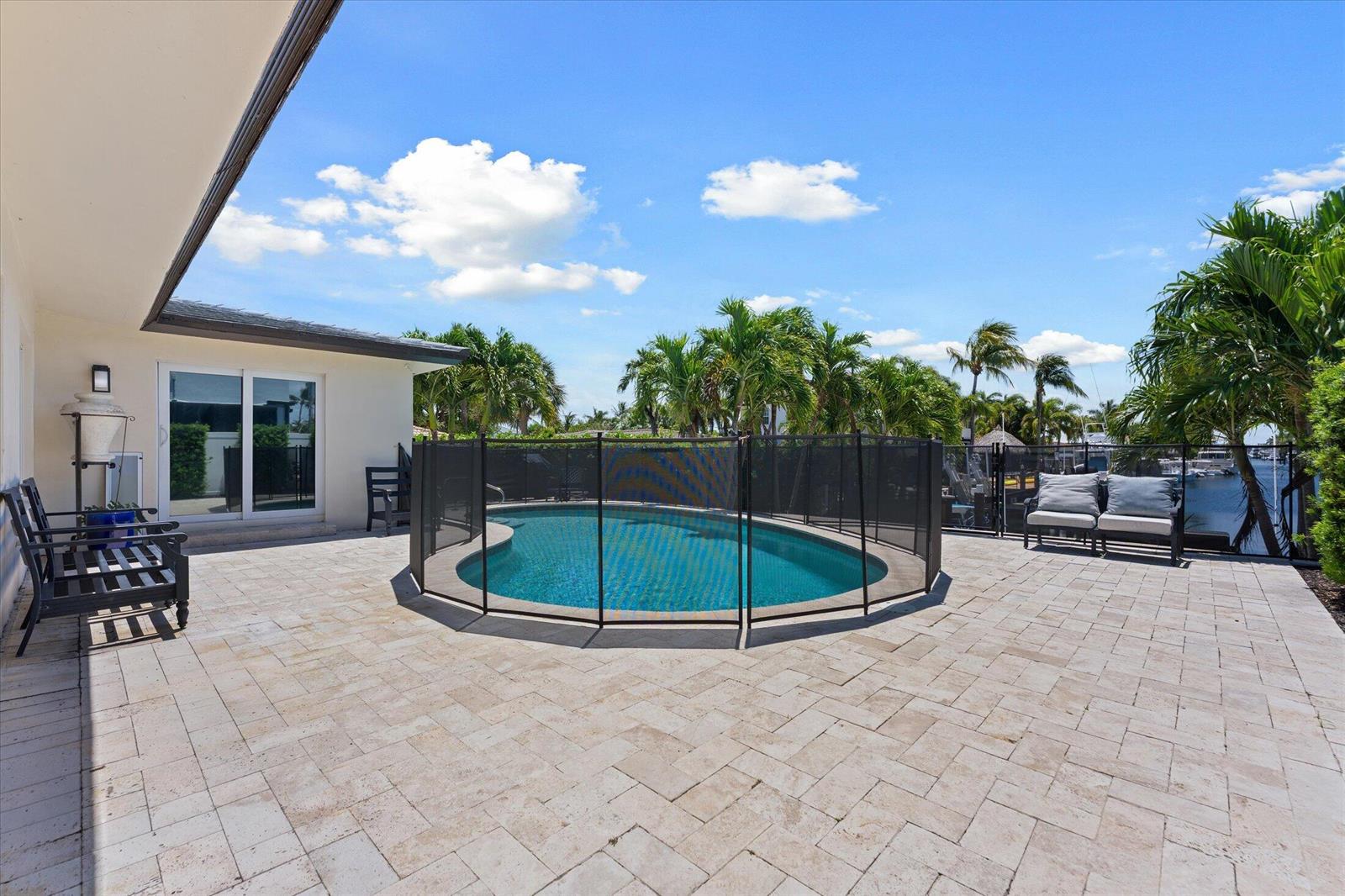 A patio with a fenced pool overlooks a canal lined with palm trees and boats — 2948 NE 35th Court, Lighthouse Point FL 33064, LIGHTHOUSE POINT, FL