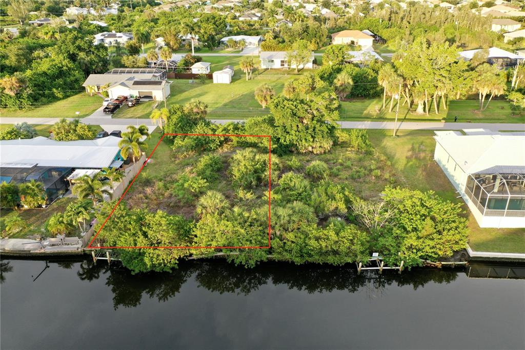 An aerial view shows a vacant, wooded waterfront lot outlined in red between two houses — 3709 WISTERIA PLACE, PUNTA GORDA, FL