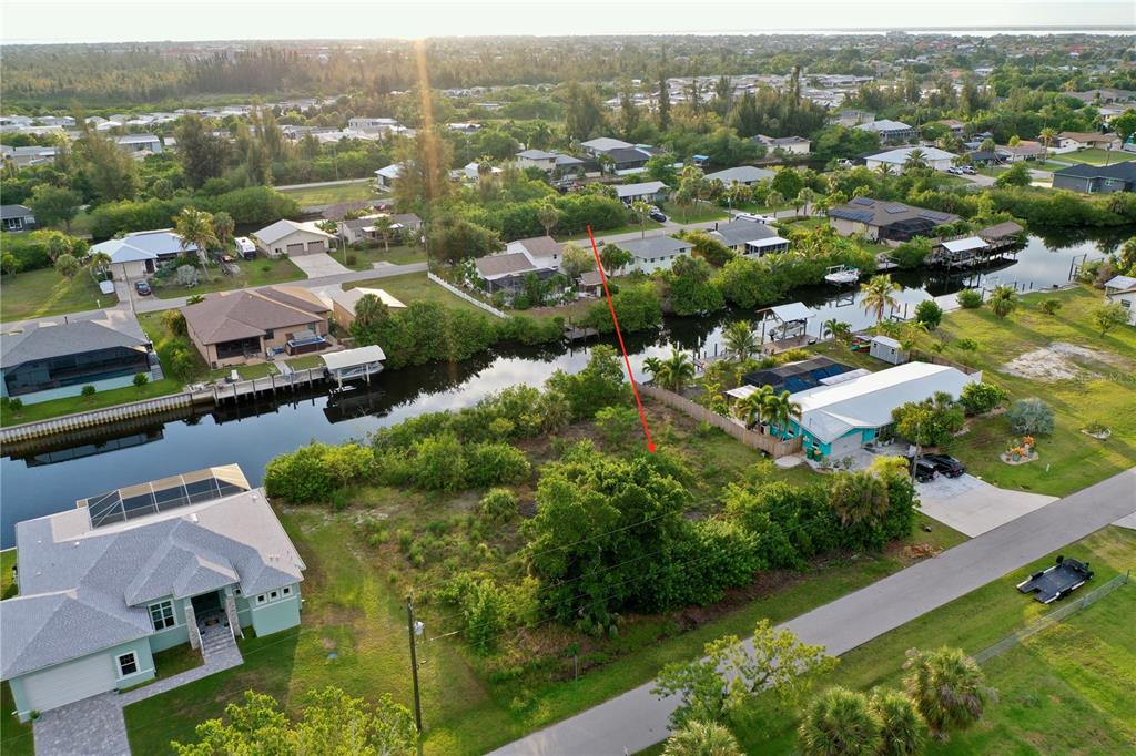 An aerial view shows a vacant waterfront lot situated between two residential houses — 3709 WISTERIA PLACE, PUNTA GORDA, FL