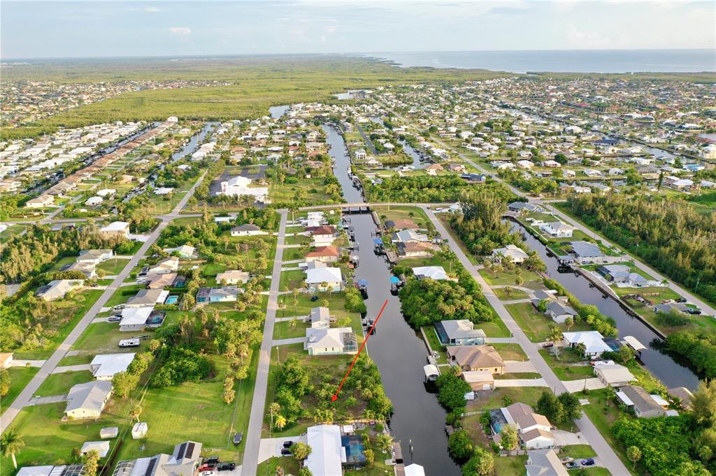An aerial view shows a vacant waterfront lot situated between residential homes along a canal — 3709 WISTERIA PLACE, PUNTA GORDA, FL