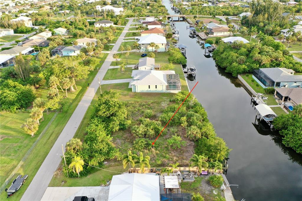 An aerial view shows a vacant waterfront lot situated between two houses along a canal — 3709 WISTERIA PLACE, PUNTA GORDA, FL