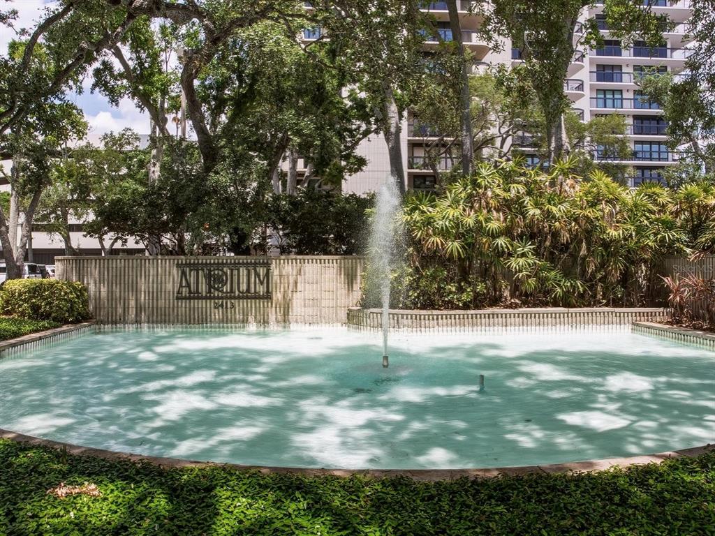 A fountain sits in front of a building sign labeled Atrium with trees behind it — 2413 BAYSHORE BOULEVARD UNIT 201, TAMPA, FL