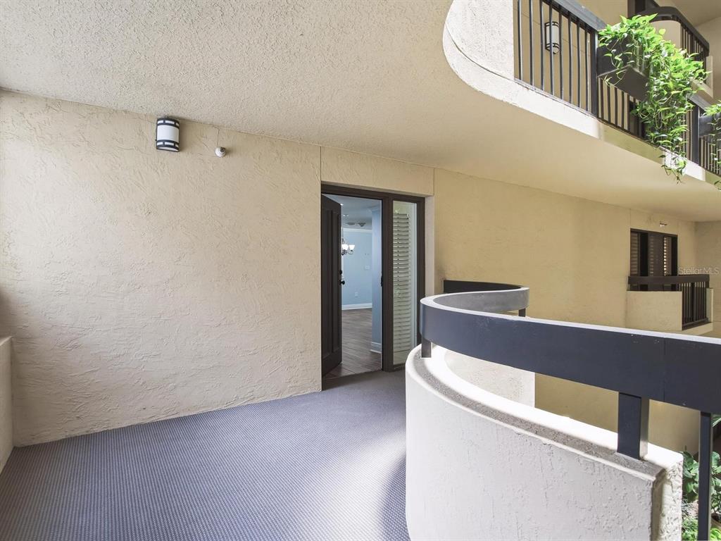 A view of a carpeted outdoor apartment balcony with a curved railing and open doorway — 2413 BAYSHORE BOULEVARD UNIT 201, TAMPA, FL