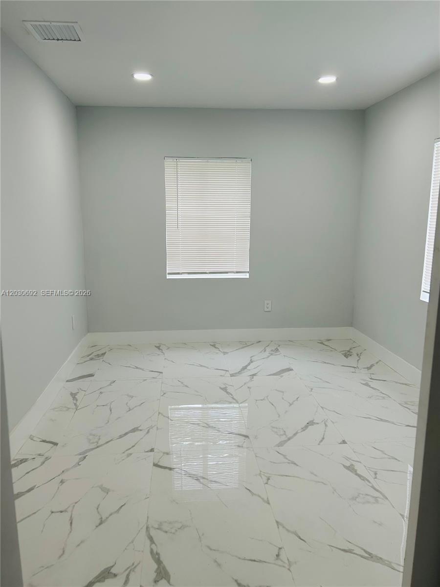 An empty room features light gray walls, white marble-patterned tile flooring, and two windows — MIAMI, FL