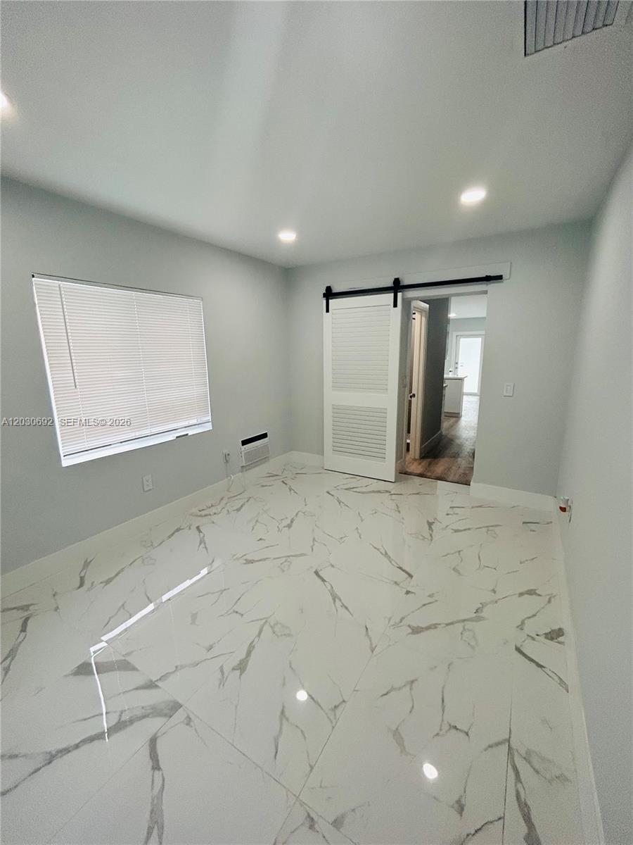 A bedroom features white marble-look tile flooring, a window with blinds, and a sliding barn door — MIAMI, FL
