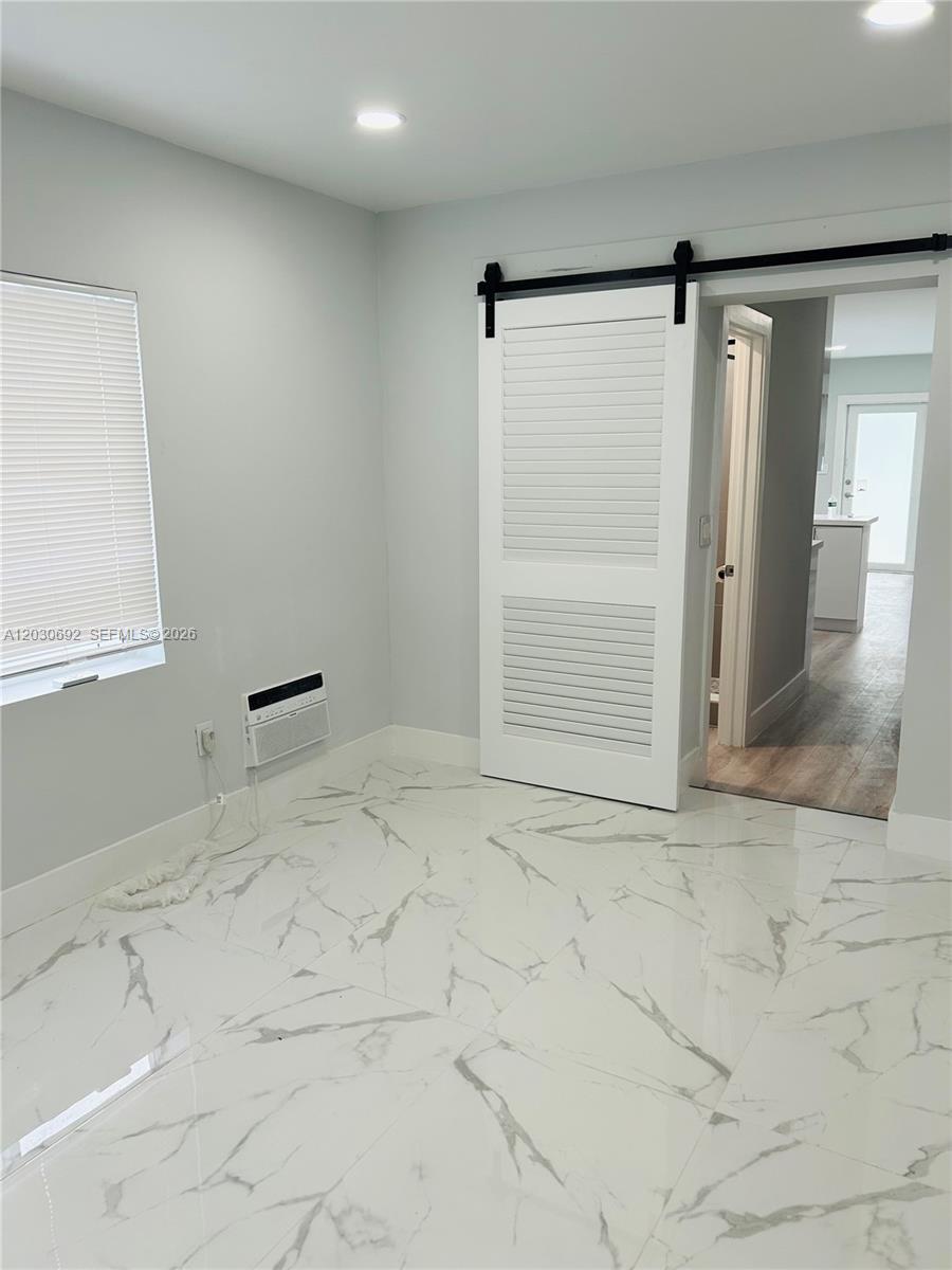A room with white marble-patterned tile flooring, a sliding barn door, and a window — MIAMI, FL
