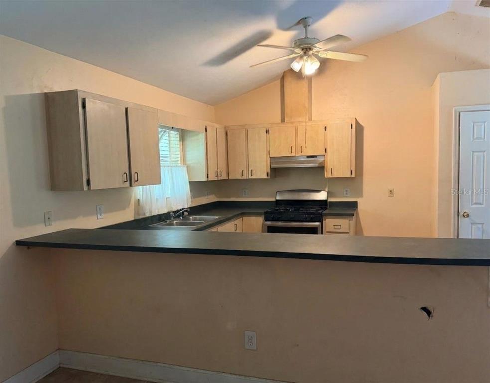 A kitchen features light wood cabinets, a black countertop, and a ceiling fan — 13521 NW 137TH PLACE, ALACHUA, FL