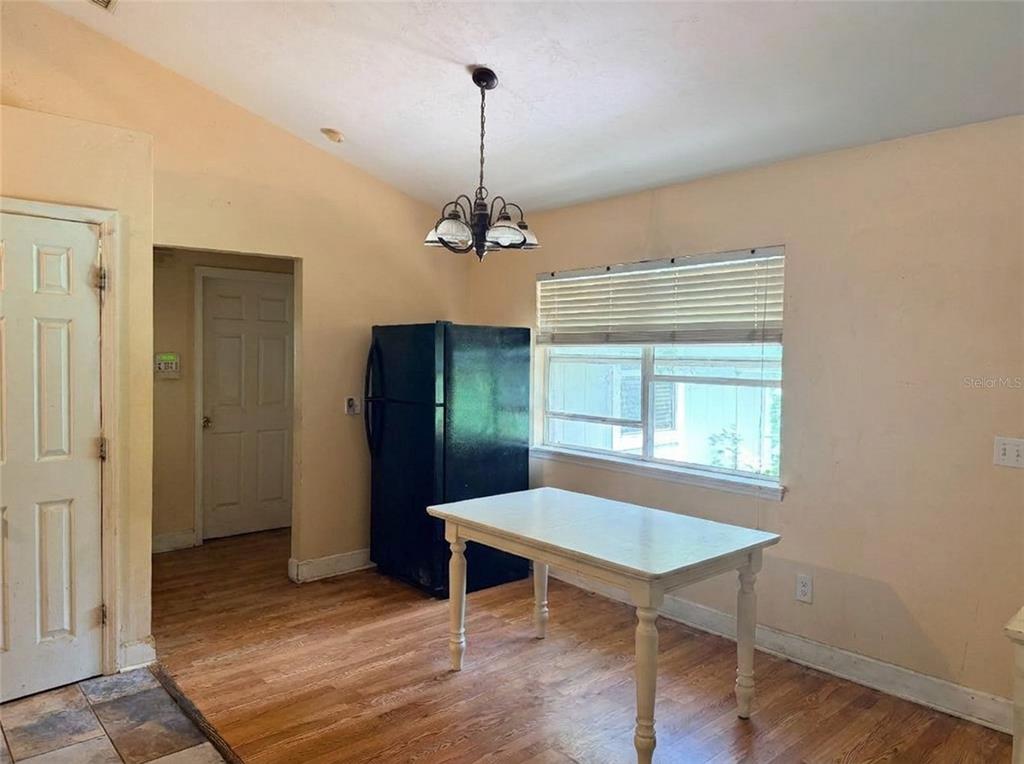 A dining area features wood flooring, a white table, a black refrigerator, and a chandelier — 13521 NW 137TH PLACE, ALACHUA, FL