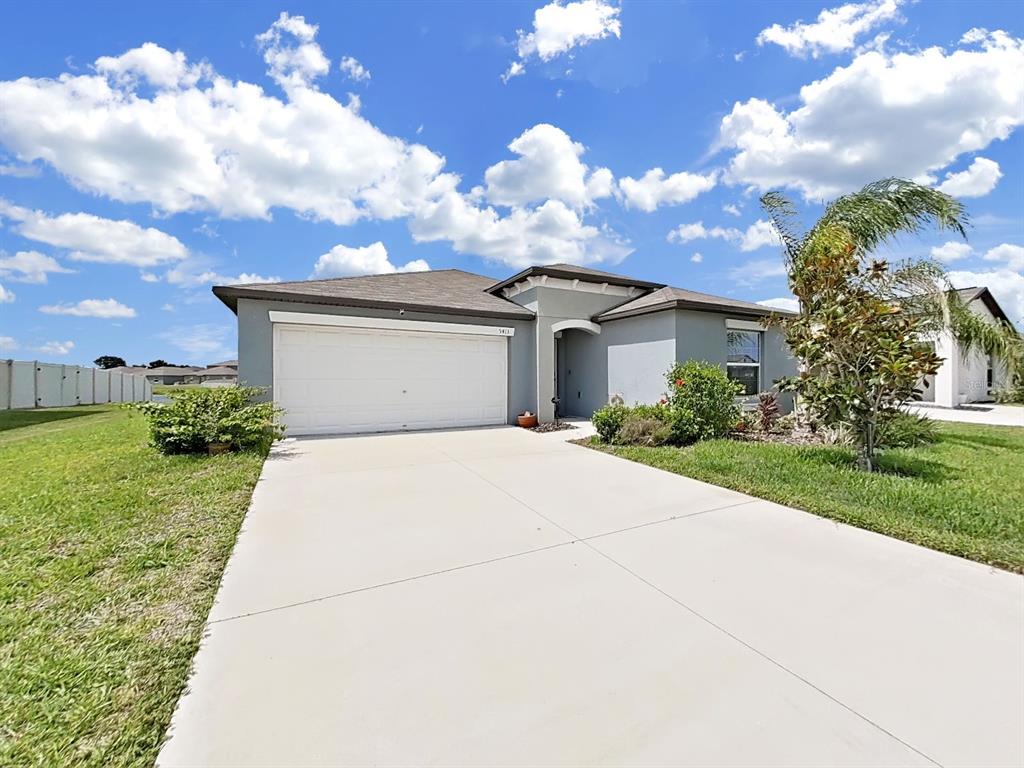 A single-story house with a white garage door, gray exterior, and a concrete driveway — 5413 BLUE AZURE DRIVE, WIMAUMA, FL
