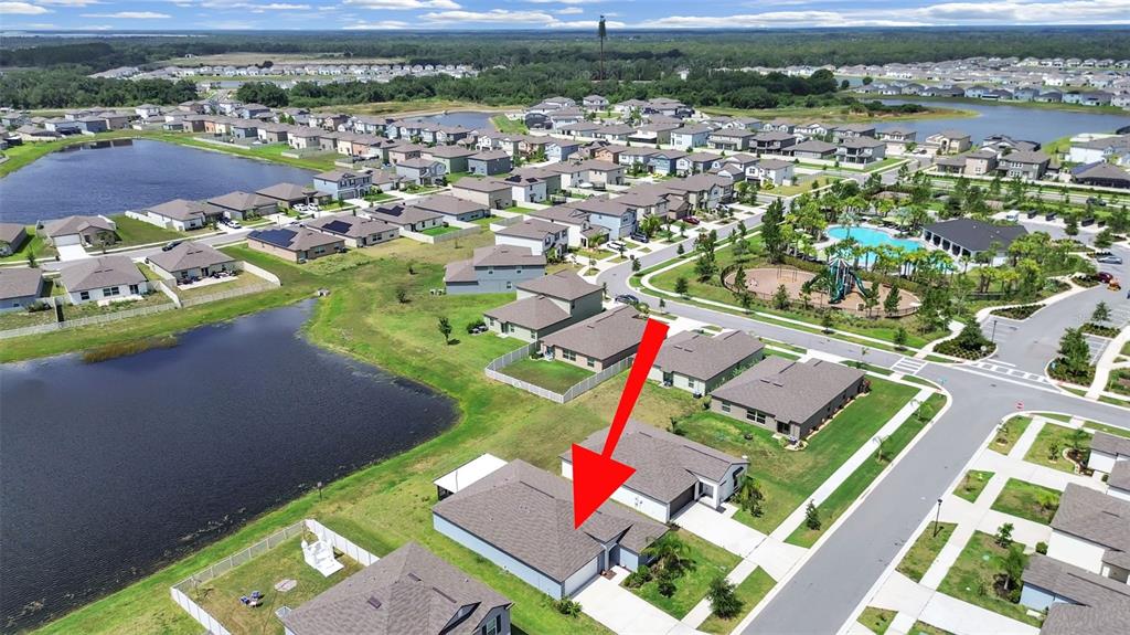 An aerial view shows a suburban house with a red arrow pointing to its roof — 5413 BLUE AZURE DRIVE, WIMAUMA, FL