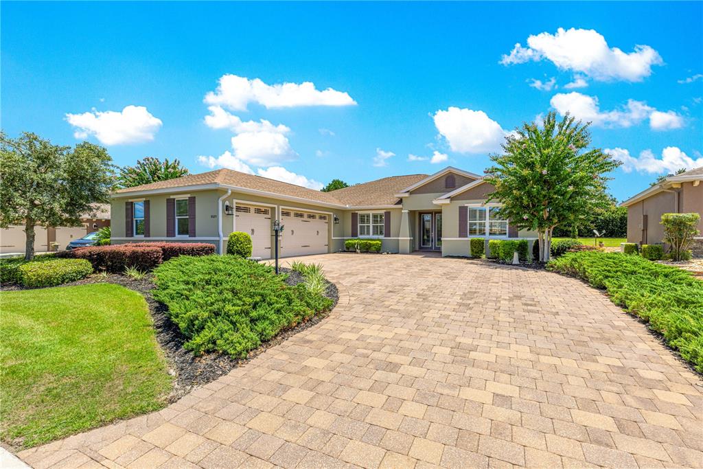 A single-story house with a paved driveway, a three-car garage, and a landscaped front yard — 8689 SW 93RD CIRCLE, OCALA, FL