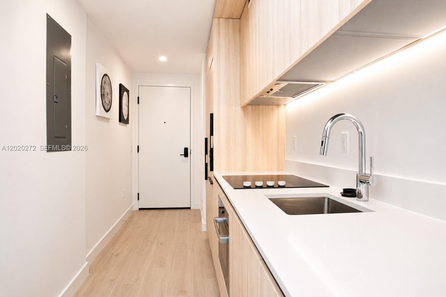 A modern kitchen features light wood cabinetry, white countertops, and a stainless steel sink — 225 N Miami Ave # 2308, Miami FL 33128, MIAMI, FL