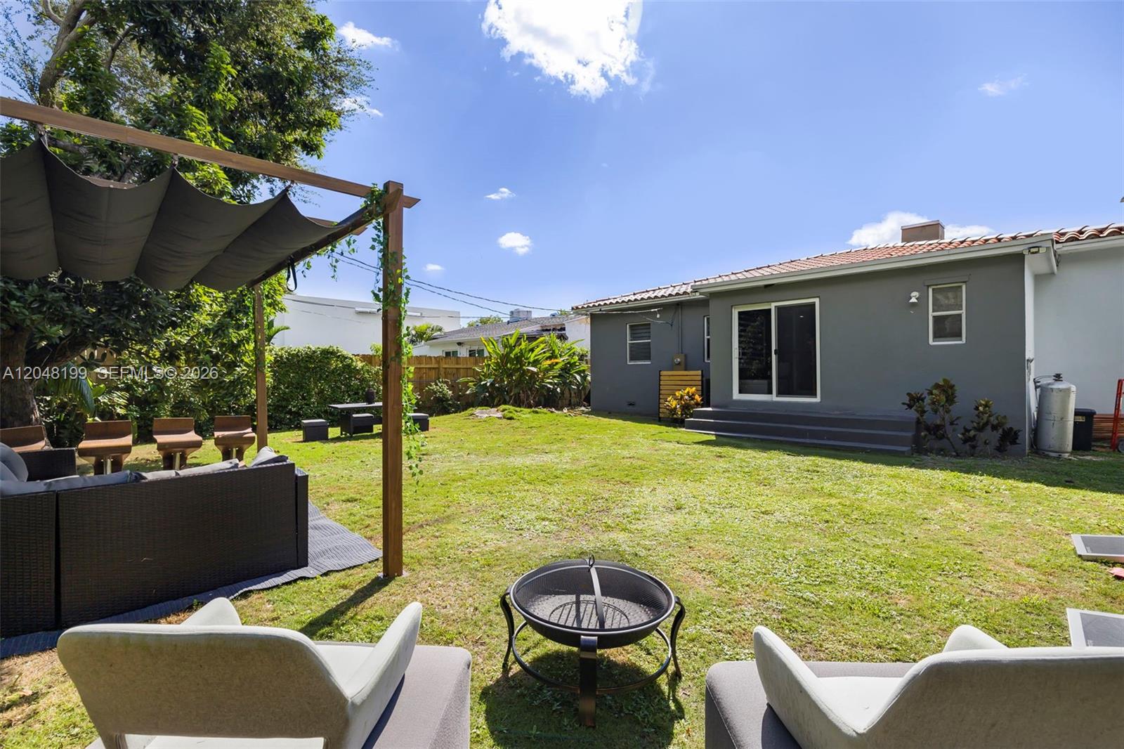 A backyard features a pergola with outdoor seating, a fire pit, and a gray house — 285 NW 45th St, Miami FL 33127, MIAMI, FL