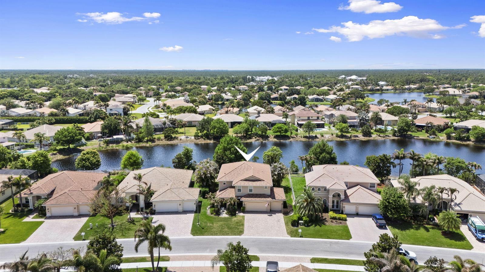 An aerial view shows a suburban neighborhood with houses bordering a lake — 1428 SE Summit Trail, Stuart FL 34997, STUART, FL