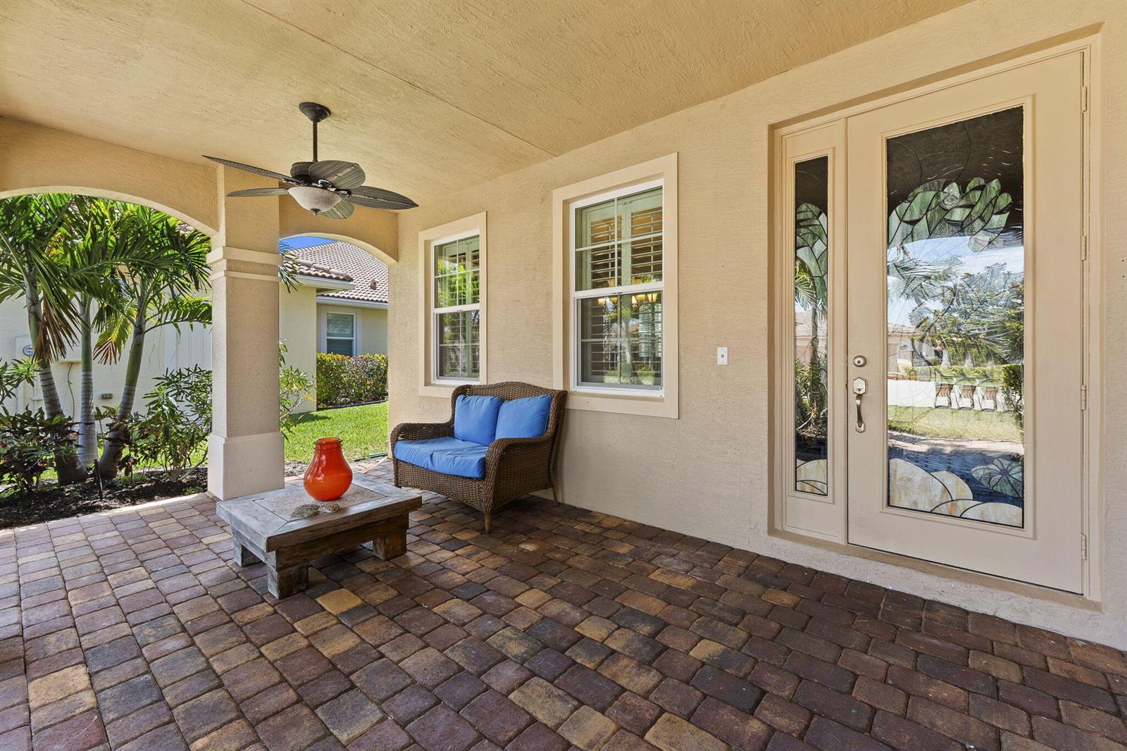 A covered patio features paver flooring, a wicker loveseat, a coffee table, and a ceiling fan — 1428 SE Summit Trail, Stuart FL 34997, STUART, FL