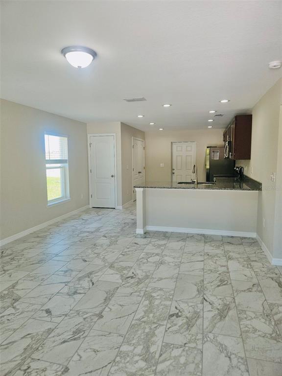 An open-concept kitchen and dining area features marble-look tile flooring and a granite breakfast bar — 328 MOUNTAIN DRIVE, BABSON PARK, FL